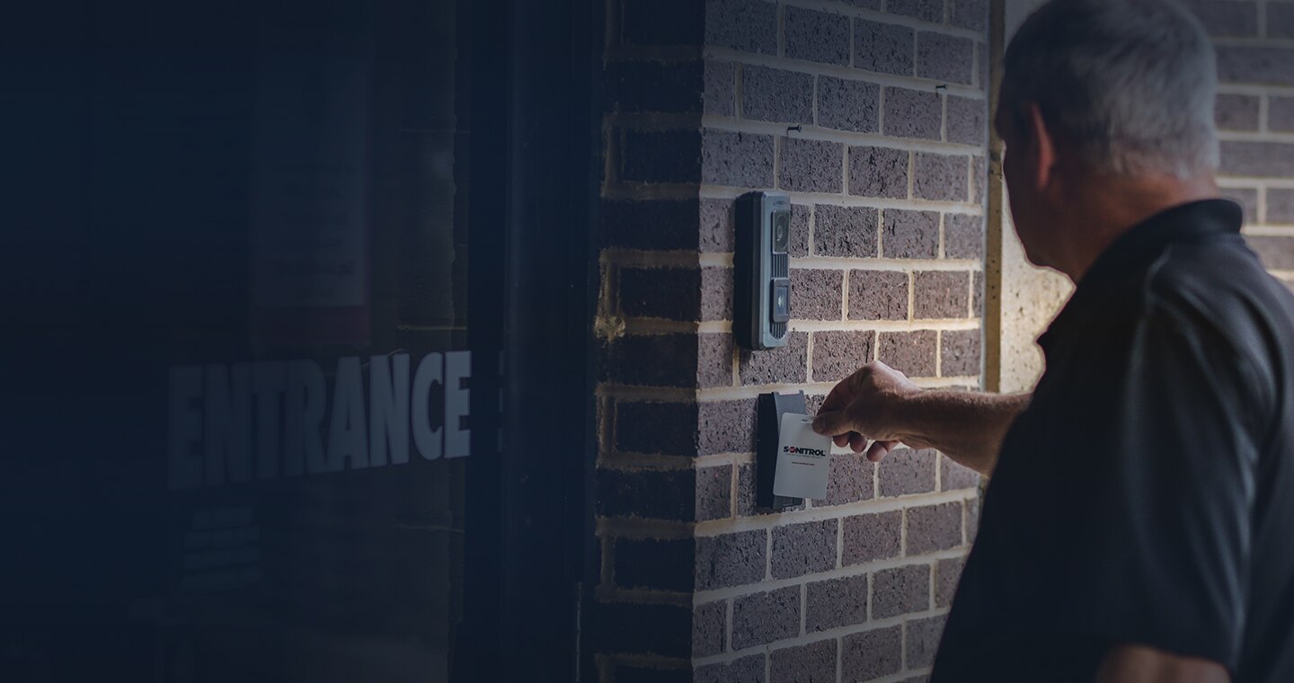 A man using his sonitrol badge to enter the building. 